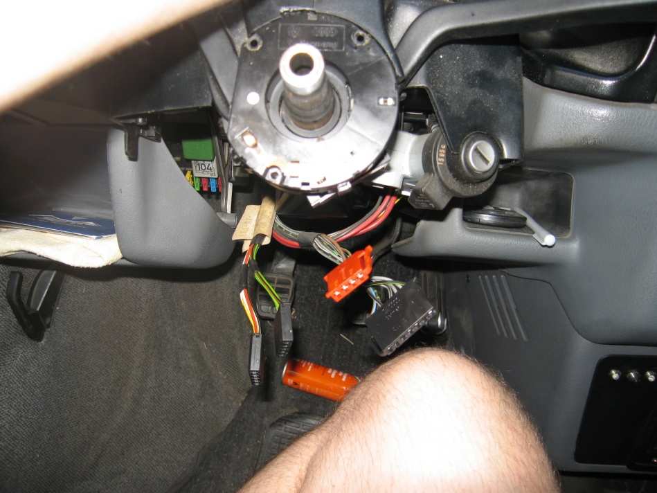 Under the steering column: the stalk switch connectors unplugged, including an orange one